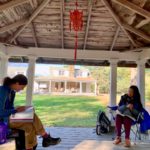 A student and teacher sit beneath a lantern in the gazebo for a Mandarin Chinese lesson